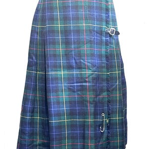 May include: A knee-length wrap skirt featuring a blue, green, and yellow plaid tartan pattern. The skirt includes a fringed edge along the front panel, a silver-toned metal safety pin closure, and a black leather strap with a silver buckle at the waist.