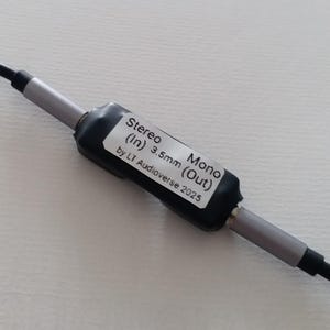 May include: A black and silver audio adapter with a label that reads "Stereo (In) 3.5mm (Out) Mono by LT Audioverse 2025." The adapter has a black cable and is designed for audio equipment.