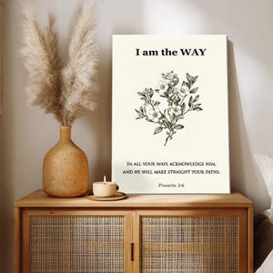 Op de afbeelding: Een canvas print met de tekst "I am the WAY" en een bloemenillustratie. De print bevat ook de tekst "IN ALL YOUR WAYS ACKNOWLEDGE HIM, AND HE WILL MAKE STRAIGHT YOUR PATHS. Proverbs 3:6". De print wordt weergegeven op een houten kast.