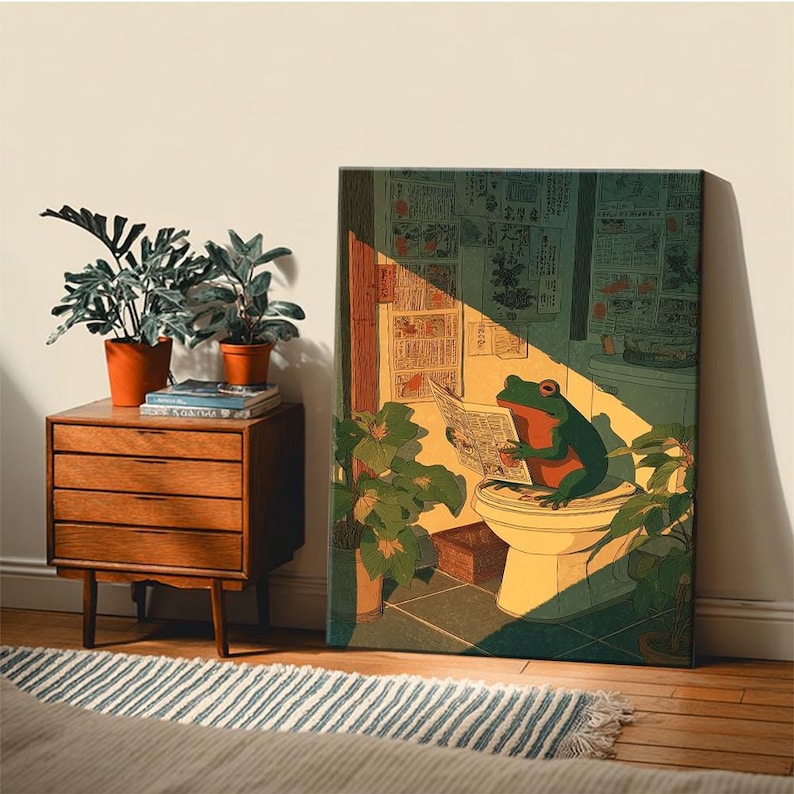 Puede incluir: Impresi&oacute;n en lienzo que representa una rana verde leyendo un peri&oacute;dico en un inodoro. La obra de arte tiene una est&eacute;tica vintage, con una paleta de colores c&aacute;lidos y un toque de humor.  Una mesita de noche de madera y plantas en macetas est&aacute;n al lado.