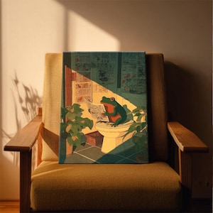 Puede incluir: Una impresi&oacute;n en lienzo que presenta una rana verde con detalles rojos, leyendo un peri&oacute;dico mientras est&aacute; sentada en un inodoro. La obra de arte est&aacute; ambientada en una escena de ba&ntilde;o con plantas y una ventana, ba&ntilde;ada por la luz del sol. La impresi&oacute;n se muestra en un sill&oacute;n amarillo.