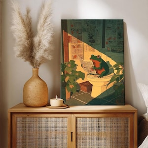 Puede incluir: Una impresi&oacute;n art&iacute;stica enmarcada representa una rana verde leyendo un peri&oacute;dico en un inodoro. La obra de arte est&aacute; ambientada en un ba&ntilde;o con plantas y luz solar. La paleta de colores incluye tonos de verde, naranja y amarillo.