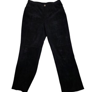 Puede incluir: Pantalones negros de pana con cierre de botón y dos bolsillos delanteros. Los pantalones tienen un diseño clásico de pierna recta y cintura alta. La tela tiene una textura suave y aterciopelada.