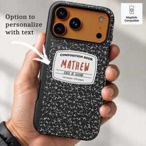 May include: A black phone case with a white speckled pattern resembling a composition notebook. The center label reads COMPOSITION BOOK, MATHEW, CLASS OF LEGEND, 100 sheets / 200 pages. The camera area is brown. Text includes Option to personalize with text.