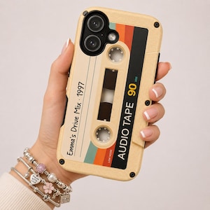 May include: A beige smartphone case featuring a retro cassette tape design with the text Emma's Drive Mix 1997 and AUDIO TAPE 90 MIN. The case includes a multi-colored stripe pattern in red, orange, and teal, with two circular cutouts for camera lenses.