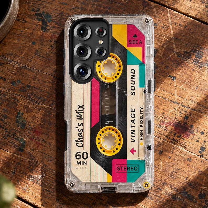 May include: A clear protective phone case featuring a graphic print of a vintage cassette tape. The design includes yellow reels, pink and teal accents, and text reading Chas's Mix, 60 MIN, VINTAGE SOUND, HIGH FIDELITY, SIDE A, and STEREO.