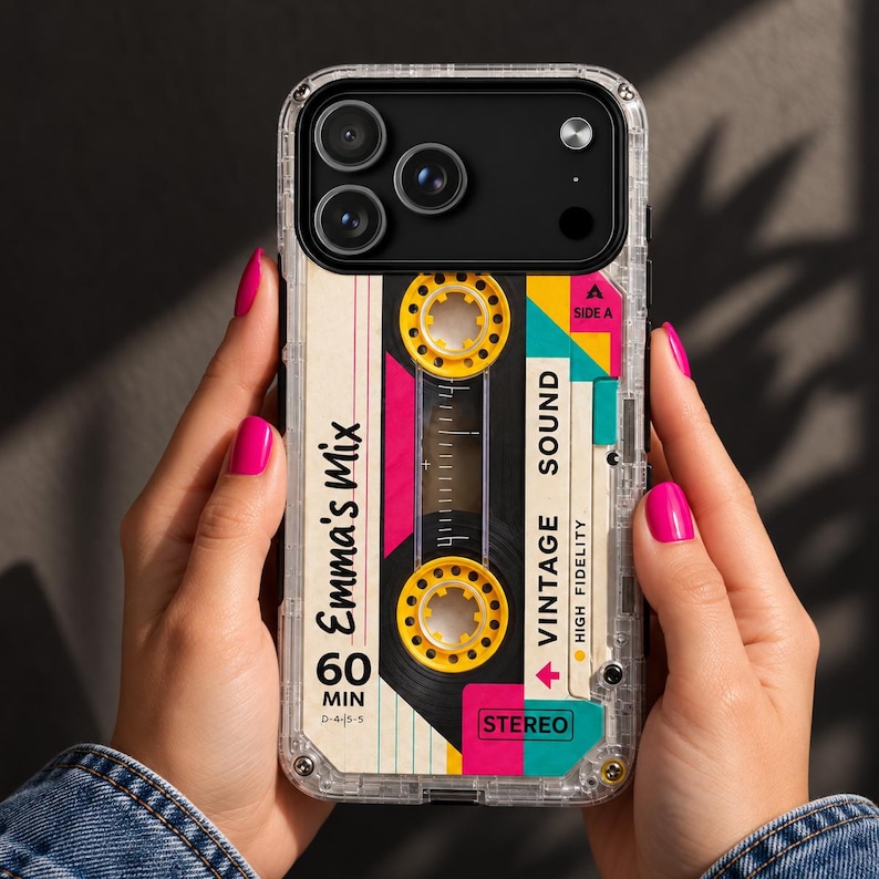May include: A clear smartphone case featuring a graphic design of a vintage cassette tape. The design includes yellow reels, pink and teal accents, and text that reads Emma's Mix, 60 MIN, VINTAGE SOUND, HIGH FIDELITY, and STEREO, with a Side A label.