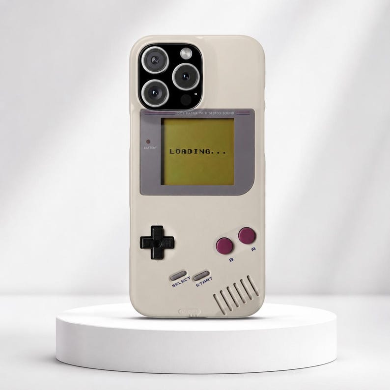 May include: A beige smartphone case featuring a retro handheld gaming console design. The screen displays the text LOADING... in black. It includes a black directional pad, two purple circular buttons labeled A and B, and silver Select and Start buttons.