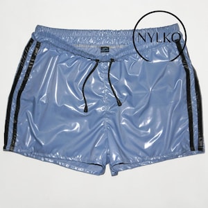 Può includere: Pantaloncini azzurri con strisce nere laterali. Questi pantaloncini lucidi hanno un cordoncino in vita. Il marchio "NYLKO" è visibile in alto a destra.