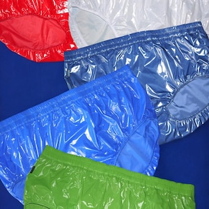 Può includere: Un assortimento di biancheria intima in plastica lucida in vari colori: rosso, bianco, blu, azzurro e verde. Gli indumenti hanno un elastico in vita e una superficie liscia e riflettente. Lo sfondo è blu.