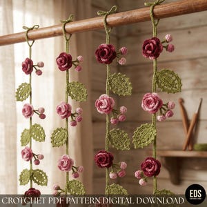 May include: Four vertical crochet garlands hanging from a wooden rod, featuring dark red and light pink roses, small pink buds, and green crocheted leaves. The text at the bottom reads CROTCHET PDF PATTERN DIGITAL DOWNLOAD.