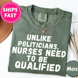 Puede incluir: Una camiseta verde oliva con el texto "UNLIKE POLITICIANS, NURSES NEED TO BE QUALIFIED" en blanco. También se ven un collar dorado y un círculo de color "Moss". Un círculo rosa con "SHIPS FAST" está en la esquina superior izquierda.