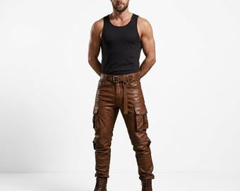 May include: A person wearing a black vest top, brown leather cargo trousers with multiple pockets, a brown belt, and brown boots. The trousers have a fitted design and a rugged aesthetic. The outfit is suitable for casual or alternative fashion.