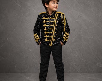 May include: A black sequined military-style jacket featuring gold braided trim, decorative gold buttons, and gold shoulder epaulets with hanging tassels, paired with plain black trousers and black dress shoes for a formal ensemble.