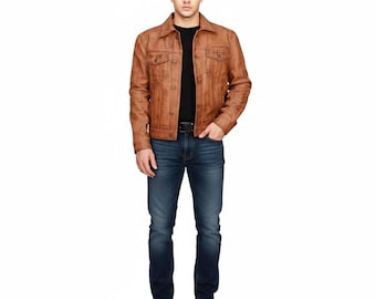May include: A tan leather jacket with a button closure, two chest pockets, and a collar. The jacket is worn over a black top, with blue jeans and brown shoes.