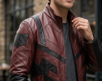 May include: A burgundy and black leather jacket with a stand-up collar and a zip closure. The jacket features black geometric accents on the shoulders and chest, and black sleeves. A stylish outerwear garment.