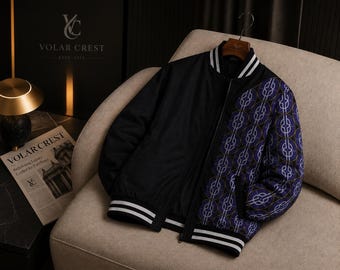May include: A black bomber jacket featuring a solid black left side and a right side patterned with a repeating purple and white circular chain-link design. The jacket includes a black ribbed collar, cuffs, and hem with two white horizontal stripes.