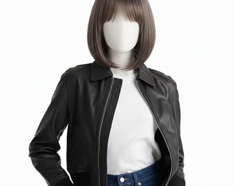 May include: A black leather jacket with a zip fastening, worn over a white t-shirt and blue jeans. The jacket has a classic bomber style with a ribbed hem and cuffs. A mannequin head is wearing a short, brown wig.