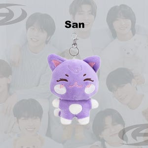 May include: A purple cat plush keychain with white accents and a silver clasp. The cat has pink inner ears, a smiling face, and a white spot on its belly. The name "San" is above the plush.