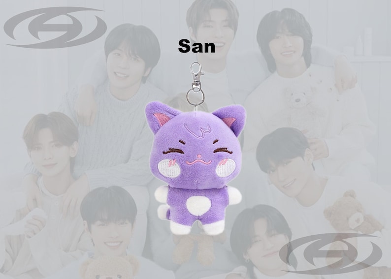 May include: A purple cat plush keychain with white accents and a silver clasp. The cat has pink inner ears, a smiling face, and a white spot on its belly. The name "San" is above the plush.
