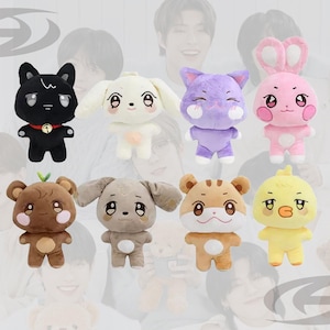 May include: A collection of nine plush animal toys in various colors. The plushies include a black cat, white dog, purple cat, pink bunny, brown bear, gray dog, orange tiger, and yellow chick. Each toy has large, expressive eyes.