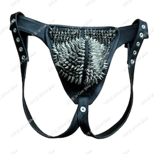 Puede incluir: Jockstrap de cuero negro con púas metálicas plateadas. El jockstrap tiene correas ajustables y un panel frontal tachonado. El diseño incluye una bolsa y una cintura con ojales para ajustar.