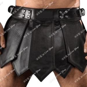 May include: Black leather kilt with a belt and buckle closure. The kilt features a series of overlapping panels and is paired with matching black wrist cuffs. The kilt is designed with a unique, edgy aesthetic.