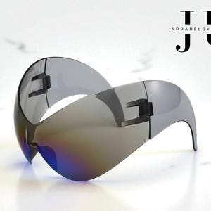 May include: Sleek, futuristic sunglasses with a wraparound design. The lenses have a gradient tint, transitioning from a dark gray to a blue hue. The frame is a metallic silver color. The text "Apparel by Joseph" is in the upper right corner.