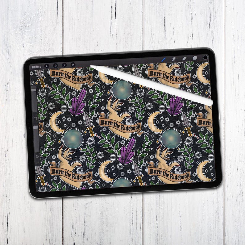 K&ouml;nnte beinhalten: Ein digitales Tablet-Bild mit einem sich wiederholenden Muster und dem Text "Burn the Rulebook". Das Design zeigt H&auml;nde, Kristalle, Monde, Dolche und florale Elemente in Lila, Gr&uuml;n und Gold auf schwarzem Hintergrund. Ein wei&szlig;er Stift liegt auf dem Bildschirm.