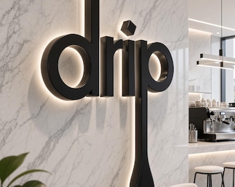 May include: A three-dimensional wall sign featuring the word drip in black, bold, sans-serif lettering. The letter p extends downward into a long, rounded drop shape. The sign is backlit with a soft white glow against a white marble wall.