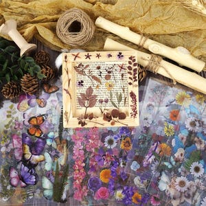 Puede incluir: Una colecci&oacute;n de materiales de manualidades que incluye un marco de madera con flores y hojas secas, pegatinas de mariposas y flores, hilo, clavijas de madera y pi&ntilde;as. La paleta de colores incluye tonos naturales de marr&oacute;n, verde y amarillo, con toques de morado y naranja.