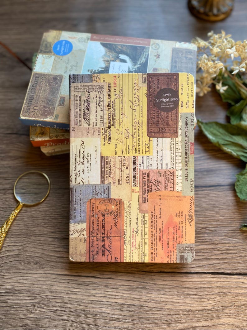May include: A stack of vintage-style notebooks with a collage of old tickets and ephemera. The top notebook features a label that reads "Kavin Sunlight soap". The color palette includes browns, tans, and faded blues, creating a nostalgic aesthetic.