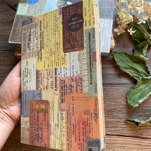 May include: A vintage-style journal with a collage of old tickets and ephemera. The cover features a mix of faded colors, including yellow, brown, and beige, with text from various railway companies. A small label reads "Kavin Sunlight soap."