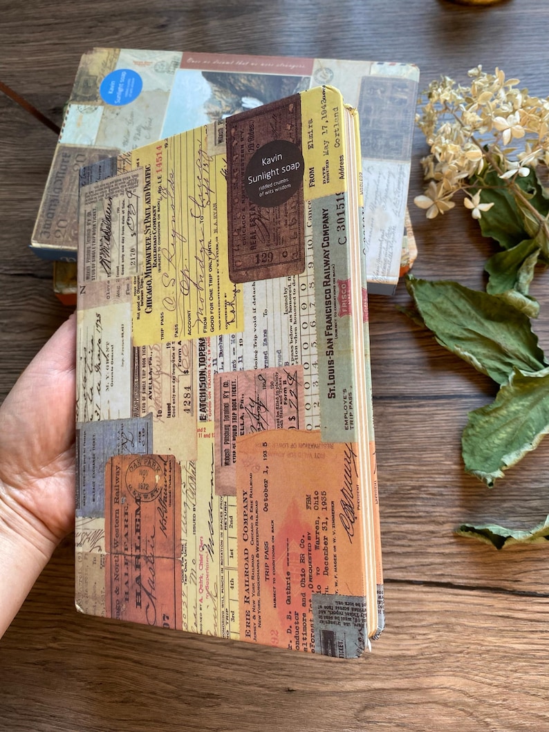 May include: A vintage-style journal with a collage of old tickets and ephemera. The cover features a mix of faded colors, including yellow, brown, and beige, with text from various railway companies. A small label reads "Kavin Sunlight soap."