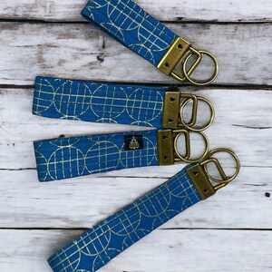 May include: Four blue and gold keychains with geometric patterns and brass key rings.