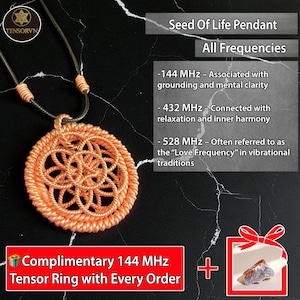 Pode incluir: Um pingente Seed of Life laranja com um design tecido, suspenso por um cordão escuro. A imagem inclui texto sobre frequências: 144 MHz, 432 MHz e 528 MHz. O pingente é apresentado em uma superfície preta.