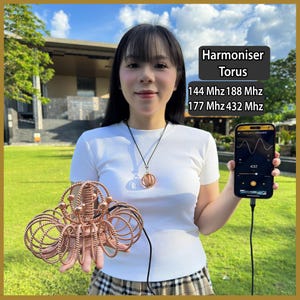 May include: A copper-colored Harmoniser Torus sculpture with intricate wire-coiled rings, accompanied by a matching pendant necklace. A smartphone displays a frequency generator app showing 432 Hz, with text listing 144 Mhz, 188 Mhz, 177 Mhz, and 432 Mhz.