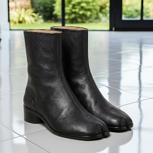 May include: A pair of black leather ankle boots with a split-toe design. The boots have a mid-height heel and a smooth, textured finish. The boots are approximately 8 inches tall.