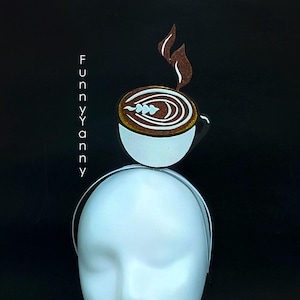 May include: A white headband featuring a coffee cup design. The coffee cup is white with a brown coffee design and steam. The text "FUNNYYANNY" is printed vertically on the left side of the image.