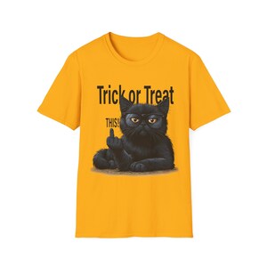 May include: A bright yellow short-sleeved t-shirt featuring a graphic of a black cat wearing glasses. The cat is making a rude hand gesture. Above the cat, the text reads Trick or Treat, and below the cat, the text reads THIS! in black font.