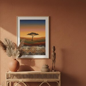 African savanna sunset art print in a white frame displayed above a boho entryway console table. The print shows a lone acacia tree silhouetted against a golden orange sky with tribal pattern border at the bottom. Styled with clay pots and pampas grass