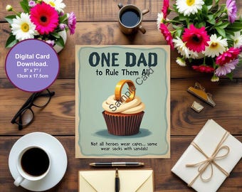 May include: A greeting card with the text "ONE DAD to Rule Them All" and a cupcake with a ring on top. The card is surrounded by flowers, a coffee cup, glasses, and a gift. The card measures 13cm x 17.5cm.