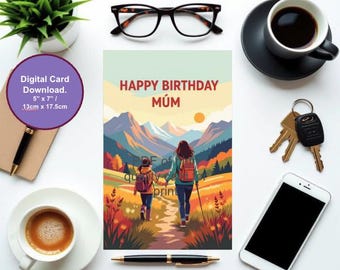 Op de afbeelding: Een wenskaart met de tekst "HAPPY BIRTHDAY MÚM" en een illustratie van twee mensen die in een berglandschap wandelen. De kaart is 13cm x 17,5cm. Andere items zijn koffie, een bril en een smartphone.