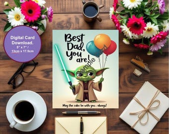 May include: A greeting card featuring the text "Best Dad, you are" and an illustration of a green alien holding a lightsaber and balloons. The card measures 13cm x 17.5cm and is surrounded by flowers, a coffee cup, and stationery.
