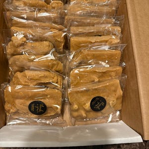 Peut inclure: Une bo&icirc;te en carton remplie de morceaux de fudge brun clair, emball&eacute;s individuellement. Chaque morceau est scell&eacute; dans du plastique transparent. Certains paquets ont un petit autocollant rond avec l'inscription "Thank you".