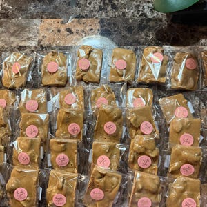 Peut inclure: Vue a&eacute;rienne de morceaux de nougatine emball&eacute;s individuellement. Chaque morceau est de couleur brun clair et scell&eacute; dans du plastique transparent. Un autocollant rose avec "merci" est sur chaque paquet.