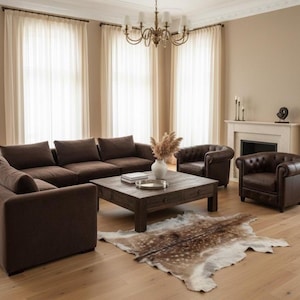 May include: A living room with brown furniture, including a sectional sofa, two armchairs, and a wooden coffee table. A decorative rug lies on the hardwood floor. The room has large windows with sheer curtains and a fireplace.