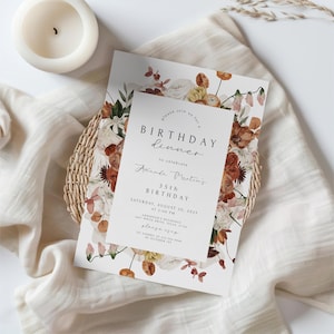 May include: A birthday dinner invitation with floral accents. The invitation features the text "BIRTHDAY dinner" and "35th BIRTHDAY" with the name "Amanda Martin". The design includes a floral border with warm tones and is set on a white background.