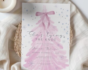 May include: A bridal shower invitation featuring a watercolor pink Christmas tree design with a bow at the top. The text reads "She's Tying The Knot" with event details for Amanda Robinson.