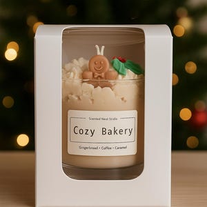 Pu&ograve; includere: Candela profumata in un barattolo di vetro, etichettata "Cozy Bakery". La candela presenta un omino di pan di zenzero e dettagli decorativi. La candela &egrave; confezionata in una scatola bianca, con note olfattive di pan di zenzero, caff&egrave; e caramello.